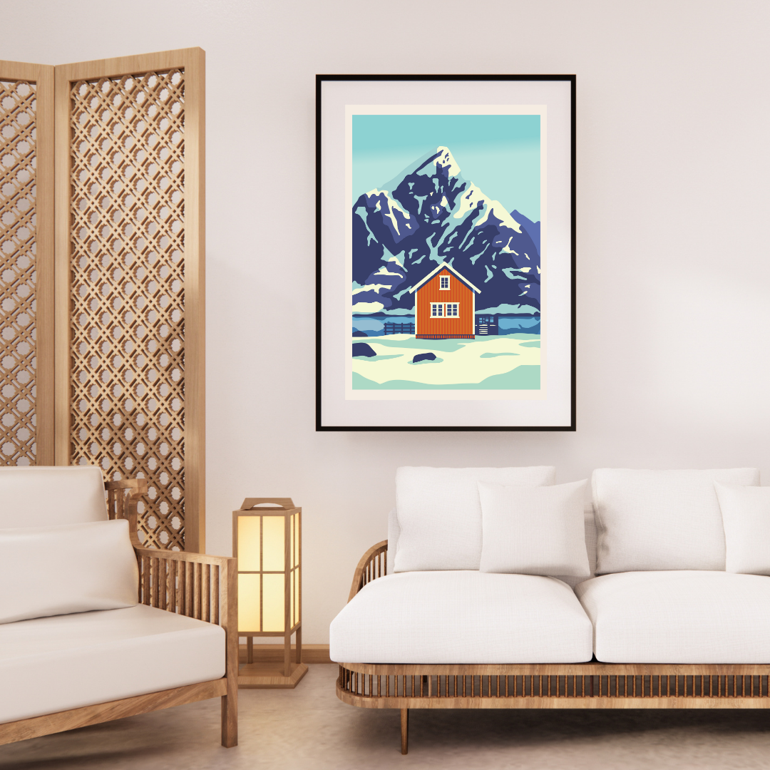 Framed artwork of the mountain Olstind in Lofoten, and the classic yellow cabin in front of the mountain. This in a living room with white walls and wooden furniture.