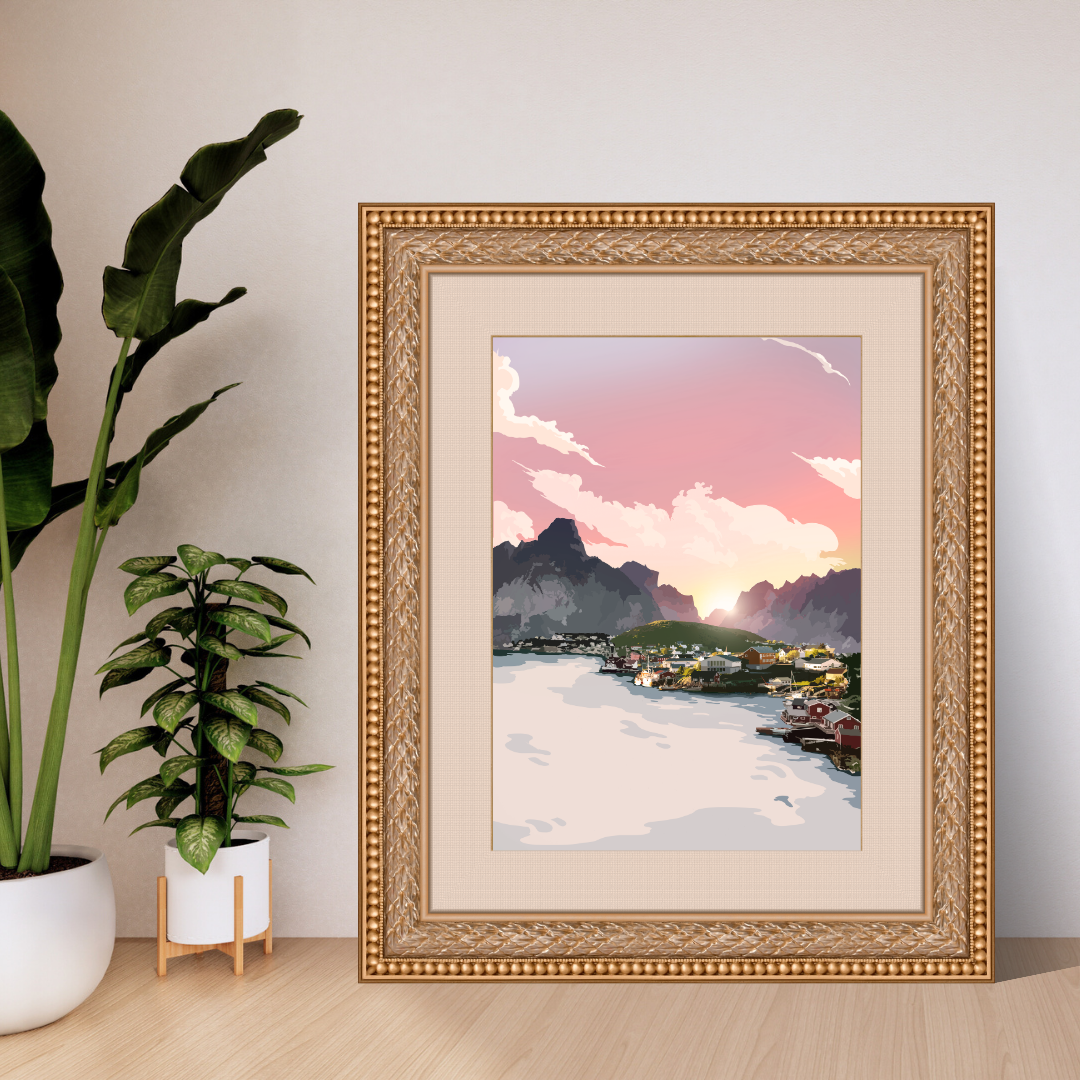 Framed artwork from Reine in Lofoten, with mountain landscape with a pink sky, placed on a wooden floor with plants around.