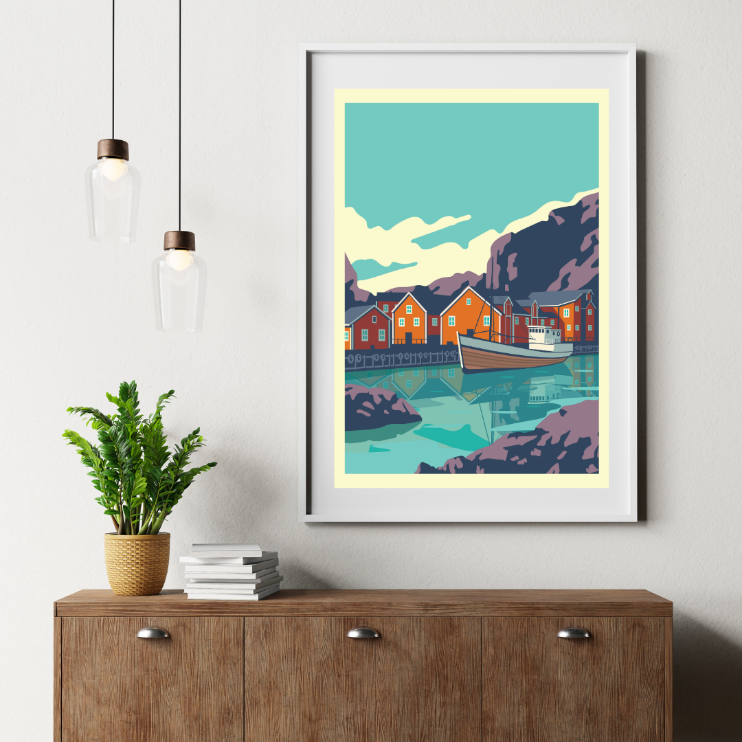 Framed artwork from Nusfjord in Lofoten, Norway. A costal scene with fisherman houses and a boat, displayed on a wall above a wooden cabinet.
