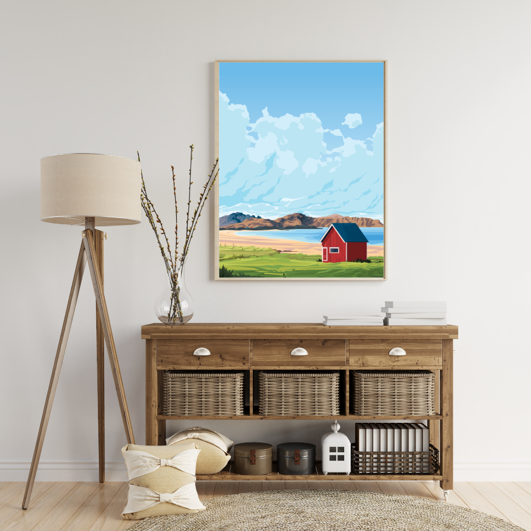 Living room with wooden sideboard, lamp, and painting of a red house. The house is the classic red cottage (rorbu) at Ramberg beach in Lofoten.