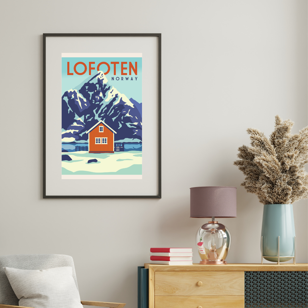 Framed artwork of Lofoten, Norway with the classic Olstind mountain and the yellow cabin on a wall above a wooden dresser.